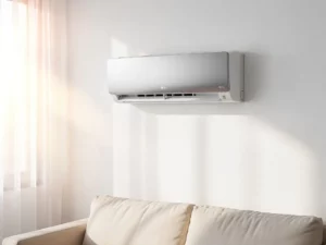 LG airconditioner aan witte woonkamermuur, zacht middagzonlicht door doorzichtige gordijnen, gedeeltelijk zichtbare bank eronder.